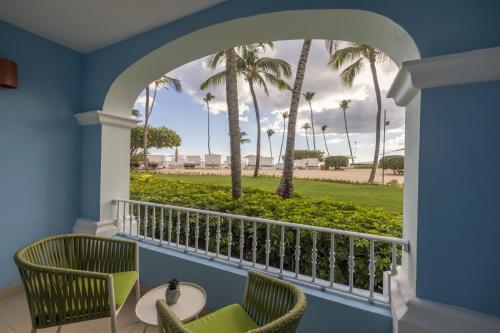 a balcony with two chairs and palm trees at Iberostar Selection Hacienda Dominicus - All Inclusive in Bayahibe