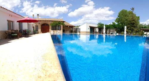 duży niebieski basen z czerwonym parasolem w obiekcie Artmonia w mieście Castalla