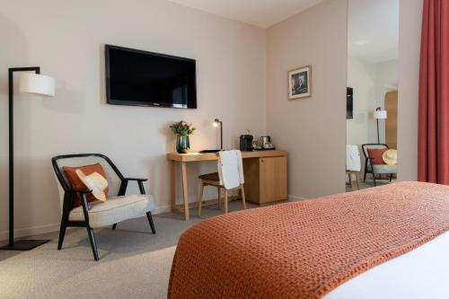 um quarto de hotel com uma cama, uma secretária e uma televisão em Hôtel Cézanne Boutique-Hôtel em Aix-en-Provence