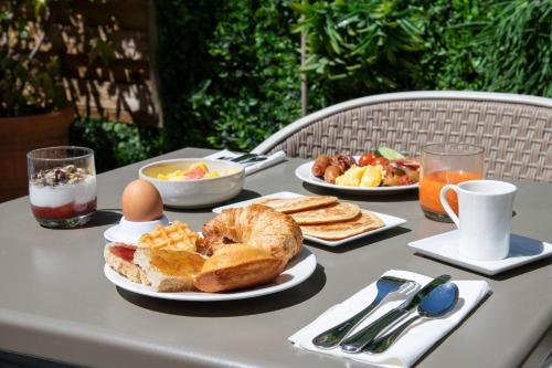 a table with a breakfast of bread and eggs and toast at Hôtel Cézanne Boutique-Hôtel in Aix-en-Provence