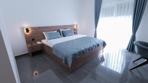 a bedroom with a bed with blue pillows and a chair at Belvedere rooms A&E in Velika Kladuša