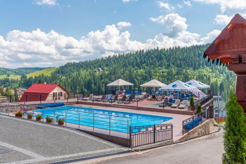 a pool at a resort with mountains in the background at Elena Spa Resort in Bukovel