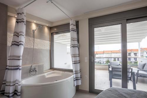 a bathroom with a tub and a large window at Villa Selena seafront in Hanioti