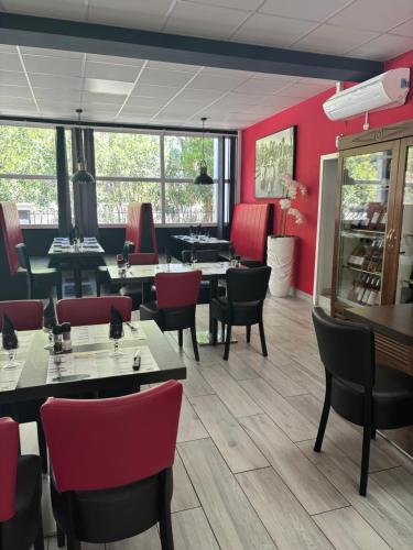 un restaurant avec des murs rouges, des tables et des chaises dans l'établissement Le Jardin des Oliviers, à Sigean