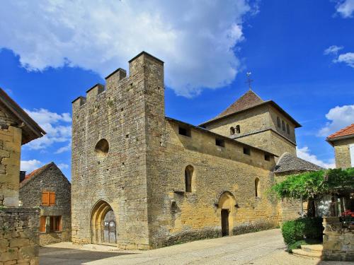 a large stone building with a tower and a church at Hôtel Bien-Être Aux Cyprès de Marquay in Marquay