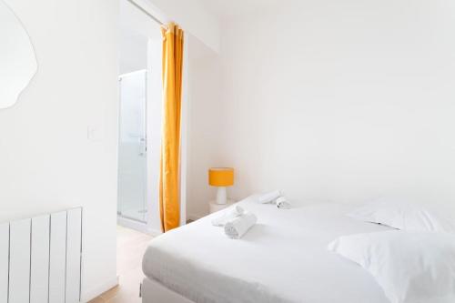 - une chambre blanche avec un lit et une lampe orange dans l'établissement Appartement confortable et fonctionnel, à Lille