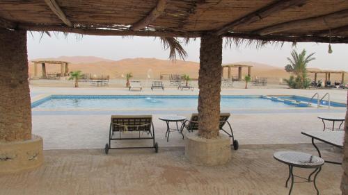 einen Pool mit Tischen und Stühlen in einem Resort in der Unterkunft SANDSTAR PALACE in Merzouga