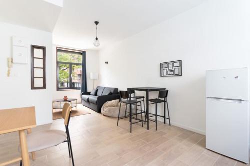 Il dispose d'une cuisine et d'un salon avec un canapé et une table. dans l'établissement Appartement confortable et fonctionnel, à Lille