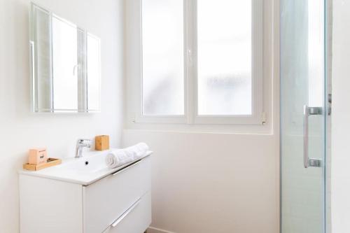 une salle de bain blanche avec un lavabo et une douche dans l'établissement Appartement confortable et fonctionnel, à Lille