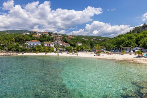 a beach with a group of people in the water at Seaside Guesthouse by JR City Apartments in Jadranovo