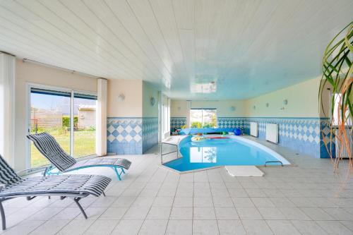 une grande pièce avec une piscine avec deux chaises dans l'établissement Piscine couverte - sauna - Maison pour 9 à Loctudy, à Loctudy