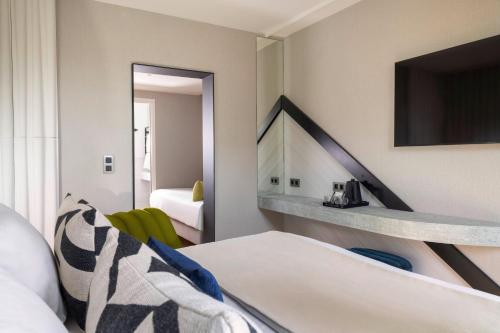 Habitación de hotel con cama y TV en Hôtel Raspail Montparnasse en París