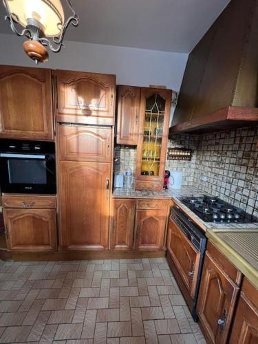 une cuisine avec des armoires en bois et un four à plaques de cuisson dans l'établissement Maison Cosy Sevran Paris CDG, à Sevran