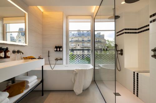baño blanco con bañera y ventana en Hôtel Raspail Montparnasse en París