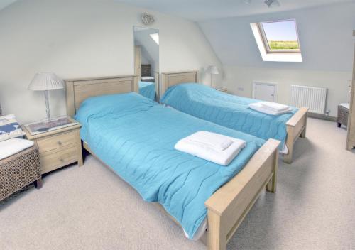 two beds with blue sheets in a bedroom at Holly Cottage in Seaton