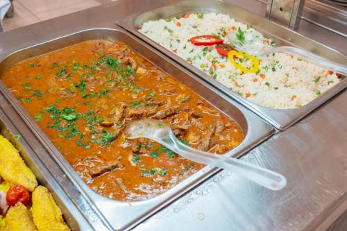 two trays of food with meat and rice on a counter at Hotel Horizont in Baška Voda