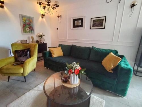uma sala de estar com um sofá verde e uma mesa em Maximilian apartman em Smederevo