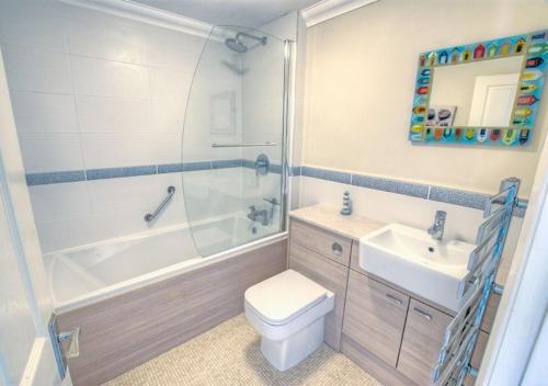 uma casa de banho com um WC, um chuveiro e um lavatório. em Tucked Away Cottage em Seaton
