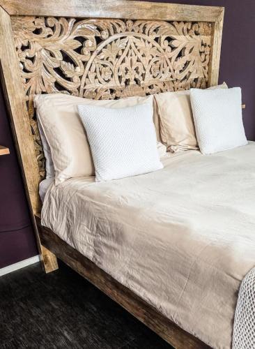 a bed with a wooden headboard and white pillows at Byron Bay Hinterlands Dreaming Woods Cabin One in Bangalow