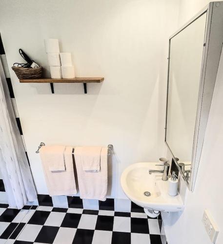 a white bathroom with a sink and a checkered floor at Byron Bay Hinterlands Dreaming Woods Cabin One in Bangalow