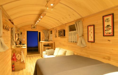 1 dormitorio con 1 cama y 1 silla en una habitación en Insolites à Chimay - Roulottes et Manoir - Roulotte Colibri, en Chimay