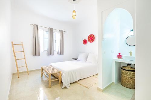 una camera da letto bianca con un letto e una sedia di Riad Dar JuMa Marrakech Suites & Penthouse avec Jacuzzi, Piscine chauffée & Spa a Marrakech