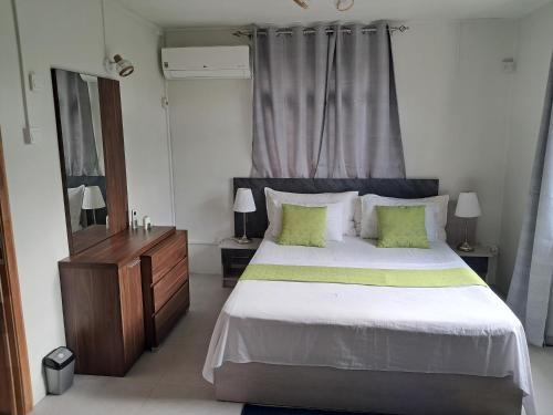 - une chambre avec un grand lit blanc et des oreillers verts dans l'établissement Riverside Holiday Home, à Grande Rivière Sud Est