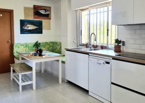 Una cocina con gabinetes blancos y un fregadero y una mesa. en La Yuca Eco Villa con piscina y jardín, en Los Alcázares