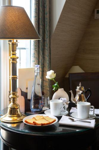 a table with a lamp and a plate of food on it at Hôtel Le Relais Saint-Germain in Paris