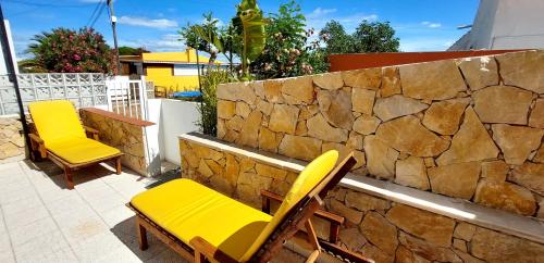 due sedie gialle e un muro di pietra su un patio di Villa Cristipaulo a Praia de Faro