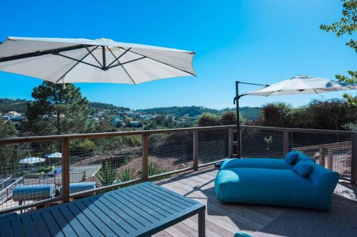 a deck with a blue couch and an umbrella at EquiNatura - Silver Coast in Caldas da Rainha