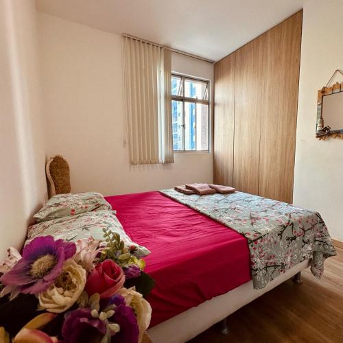 um quarto com uma cama com um cobertor vermelho e uma janela em Apê Curitiba I Familiar, tranquilo e sossegado em Belo Horizonte