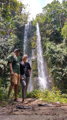 two people standing in front of a waterfall at Alfarizi homestay in Tetebatu