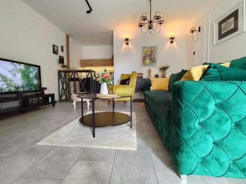 uma sala de estar com um sofá verde e uma televisão em Maximilian apartman em Smederevo