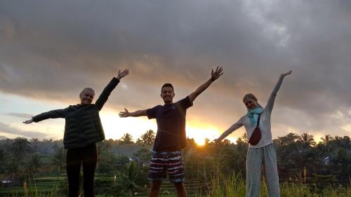 a group of three people standing with their arms up at Alfarizi homestay in Tetebatu