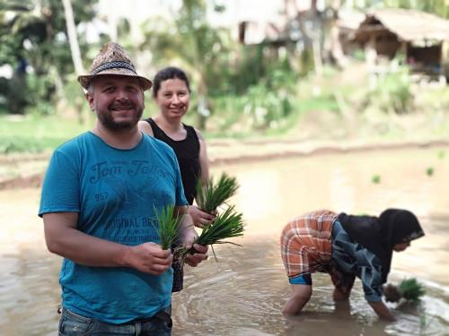 a man and woman standing in the water holding plants at Alfarizi homestay in Tetebatu
