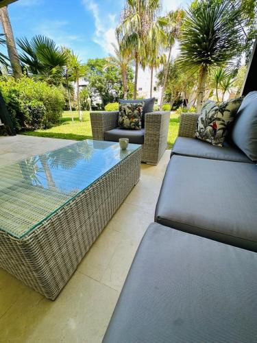 a patio with wicker furniture and a glass table at Charming Villa, Breathtaking Garden View in Casablanca