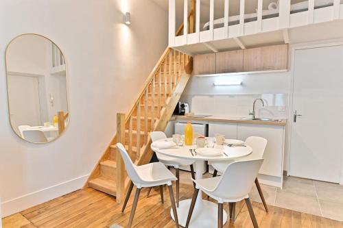 une cuisine et une salle à manger avec une table et des chaises blanches dans l'établissement Loft Central #Marais #Rivoli, à Paris