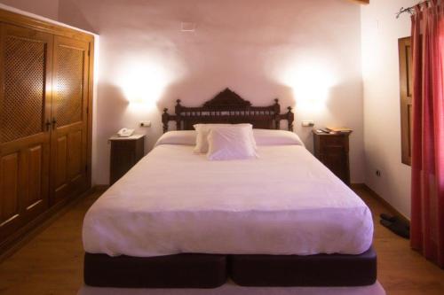 a bedroom with a large bed with white sheets and pillows at Hospedium Hotel Rural Abadía de Yuste in Cuacos de Yuste