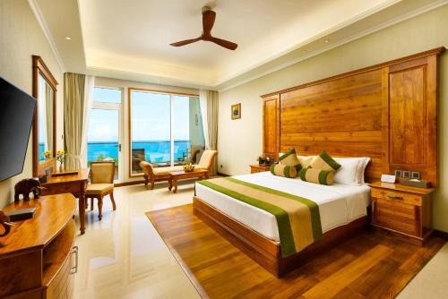 a bedroom with a bed and a desk and a television at Araliya Beach Resort & Spa Unawatuna- Where you meet the sea all year in Unawatuna