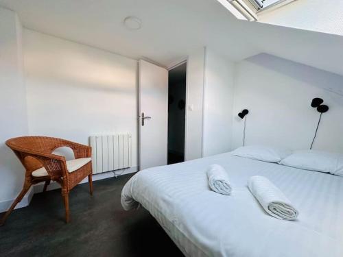une chambre avec un lit blanc et une chaise dans l'établissement Lakanal 9 - Appart Prébendes Tours, à Tours
