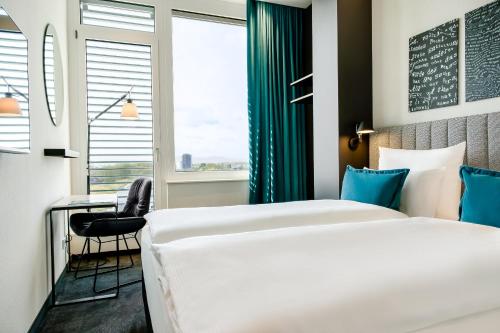 a hotel room with two beds and a desk at Motel One Karlsruhe in Karlsruhe