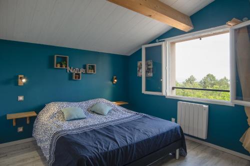 a blue bedroom with a bed and a window at Villa La Fenière in Payzac