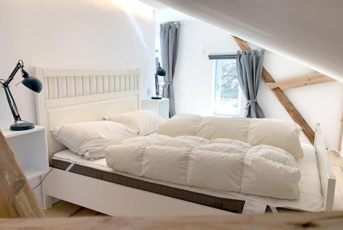 een bed met witte lakens en kussens in een kamer bij Anker in Waabs