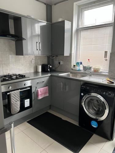 a kitchen with a washing machine and a sink at Dane Guest House Free Parking Fast WiFi Modern Living in Burnley