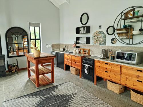 une grande cuisine avec des placards en bois et un four micro-ondes dans l'établissement Klawerjas Flute Cottage, à Robertson