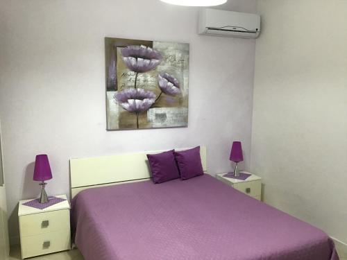 ノート・マリーナにあるB&B Villa Taniaのベッドルーム1室(紫色のベッド1台、紫色のランプ2つ付)