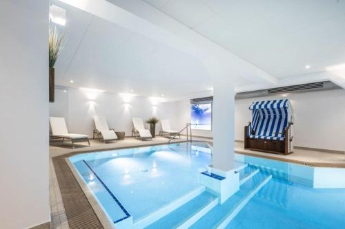 uma piscina num quarto de hotel com cadeiras e uma piscina em Strandburg 207 em Juist