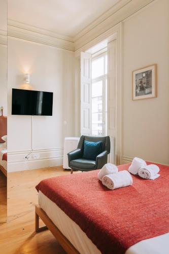a bedroom with a bed with a chair and a television at Oporto Maison Palace in Porto