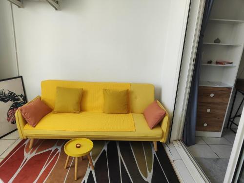 a yellow couch with pillows in a room at Studio Vanille - Vue Mer in Saint-Denis